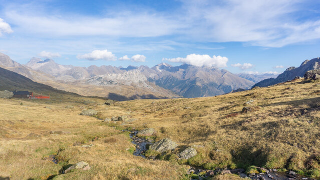 A scenic view of a mountain valley with a stream running through it and mountains in the distance