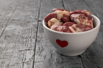 Fresh Chicken Hearts in White Bowl with Red Heart on Rustic Wooden Table