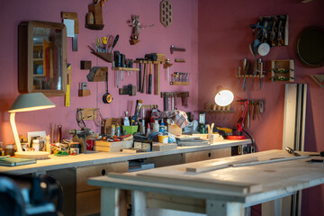 Interior of carpentry workshop with table, space filled with materials, equipment, tools hanging on wall, ideal workplace for creativity and craftsmanship, small business producing furniture items.