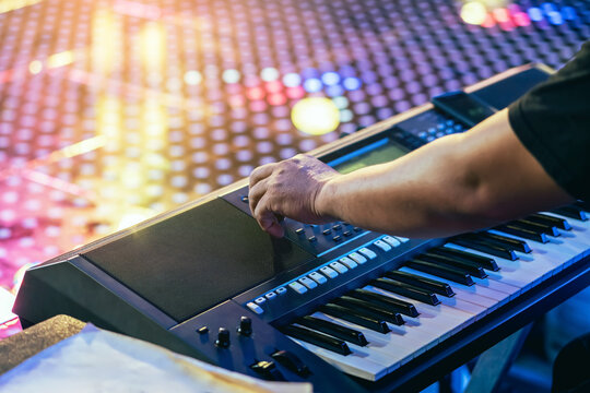 Hands of male musician press digital electronic keyboard synthesizers on concert stage. Pianist man hands play the keys of electronic piano. Piano music pianist hand playing. Selective focus on hand. - Powered by Adobe