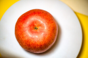 The apple on the white plate is cut in half with a knife