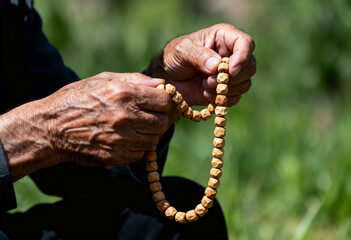 Elderly muslim man hands holding prayer beads, performing ritual prayer, honoring spirituality and fathers day