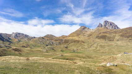A scenic view of mountainous terrain with a blue sky and scattered clouds on a sunny day outdoors