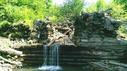 Stream water through wooden dam, mountain river closeup