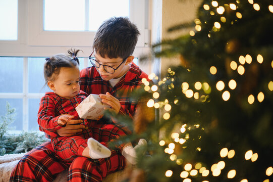 Children in plaid pajamas celebrating christmas with a gift