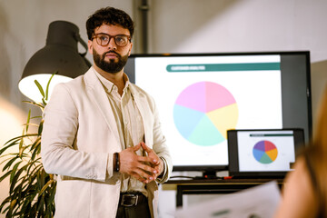 Business professional presents colorful pie chart during a team meeting in a modern office space in the afternoon