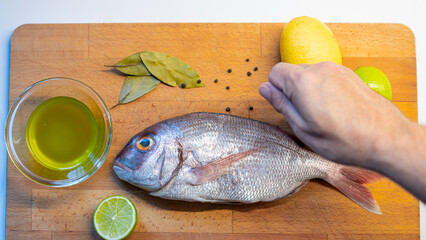 fresh fish with lemon and spices on the wood board, Greece
