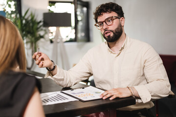 Business meeting in modern office with businessman presenting financial data to client and discussing strategy