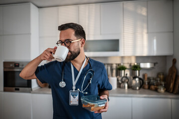 Healthcare worker having coffee and lunch box in kitchen