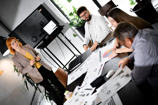 Business strategy meeting discussing progress and planning in a modern office setting with a diverse team of professionals