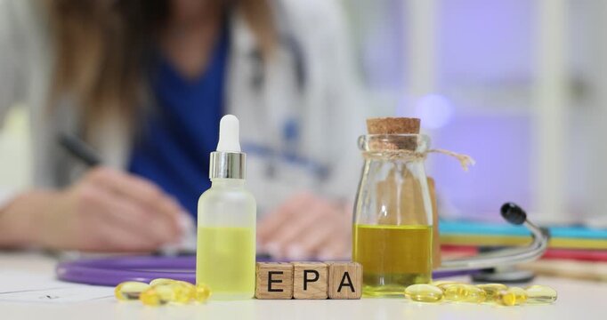 Wooden blocks spell word EPA on bright medical desk. Woman doctor writes dosage plan studying fish oil capsules for patient heart health support