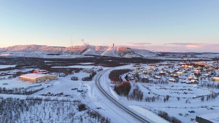 Kiruna, Sweden, aerial winter view over the iron ore mine, during sunrise just before the polar night sets it. Houses and streets in the foreground, part of the city that will be moved