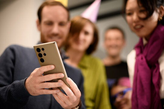 Group of friends celebrating with a smartphone at a social gathering in a cozy indoor setting during an evening party