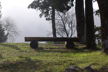 Wooden bench on the mountain. Light snow is falling, Idyllic view.