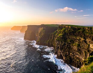 Green cliffs meet the ocean under a bright sky at sunset, with waves crashing