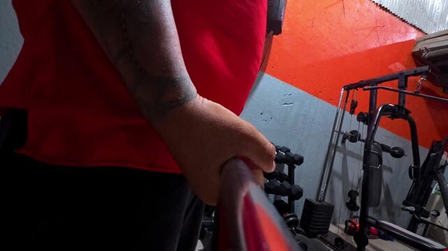 POV video of a plus size man holding a bar during his workout at the gym.