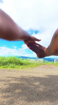 POV video of an unrecognizable person stretching their hands and arms outdoors on a sunny day.
