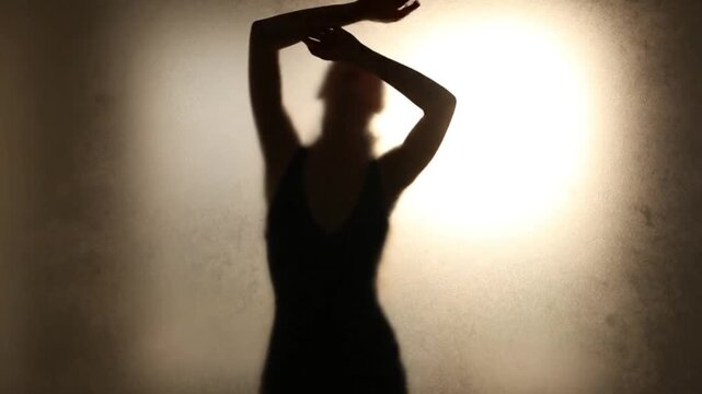 Silhouette of woman posing behind diffused screen, artistic and mysterious