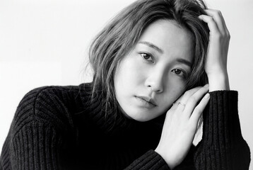 A portrait of a woman expressing emotion and introspection with beauty and serenity in a monochrome atmosphere where soft light enhances a close up sense of contemplation