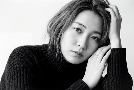 A portrait of a woman expressing emotion and introspection with beauty and serenity in a monochrome atmosphere where soft light enhances a close up sense of contemplation