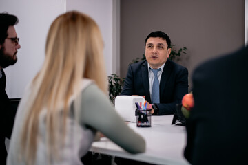 Business professionals engaged in a group discussion around a desk in an office.