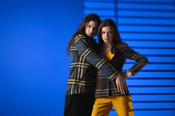 Naklejka premium Twins showcase stylish fashion with confidence in vibrant blue backdrop