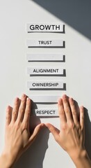Growth trust alignment ownership respect teamwork hands arranging word tiles on white surface convey focused leadership and inspiring collaboration