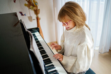 Little girl playing piano at home. Happy child practices music instrument © Irina Schmidt