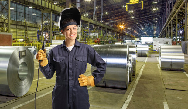 Women factory workers, female welder in a uniform with a welding machine