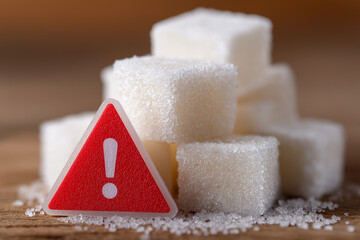 Warning Sign and White Sugar Cubes on Wooden Table Highlighting Health Risk