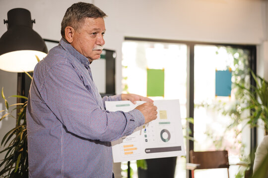 Businessman presents financial report during a meeting in a modern office space filled with plants and natural light