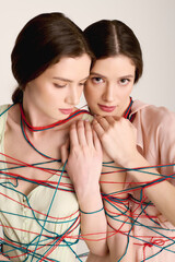 Young twin sisters showcase striking fashion in vibrant colors while connected by colorful strings