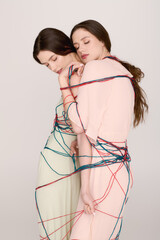 Twin sisters elegantly wrapped in colorful threads showcase unique fashion artistry