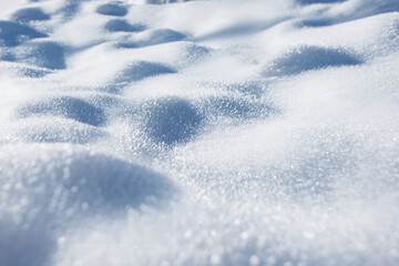 Obraz premium soft, close-up view of fresh, untouched snow shimmering in bright sunlight. The surface shows gentle curves and subtle shadows, highlighting the sparkling texture of the snow crystals. Winter snow.