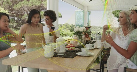 Gathering five adults wearing light green dress and white blouse at sunroom table, with teapots © vectorfusionart
