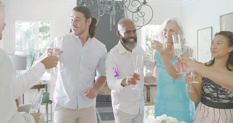 Naklejka premium Standing friends in smart clothes holding champagne flutes and toasting at home with centerpiece