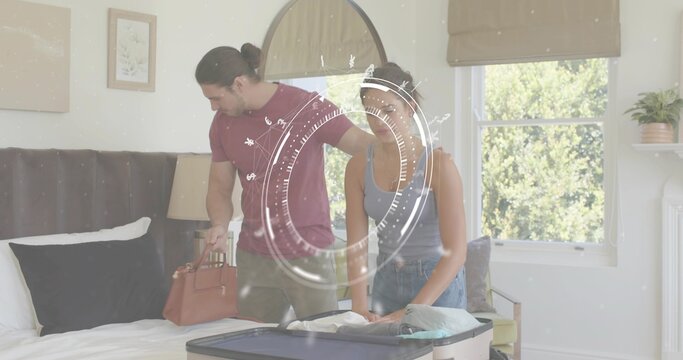 Packing couple wearing casual clothes arranging open suitcase on bed, placing tan leather handbag