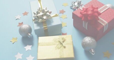 Displaying light-blue red gold wrapped gifts on pale-blue table with silver ornaments star confetti