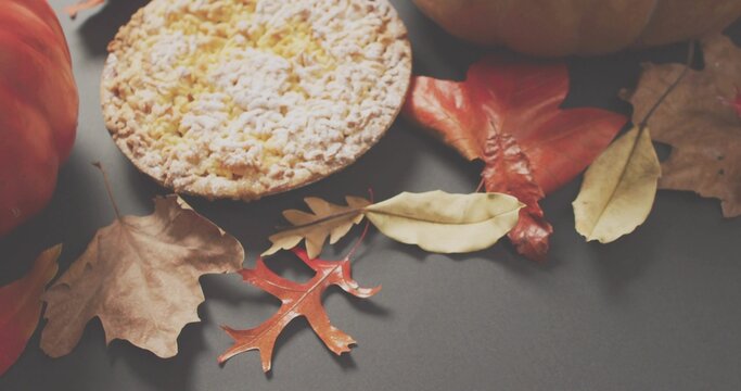 Displaying small crumbed tart sitting on gray table at home, with dried autumn leaves and pumpkins - Powered by Adobe
