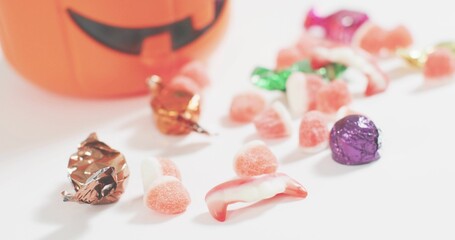Showing Halloween candy cluster on white table, with pink gumdrops, foil chocolates, blurred bucket