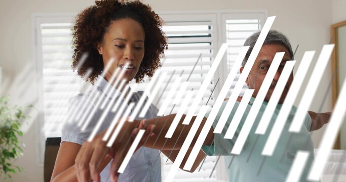 Guiding woman helping senior lifting arm in home near white shutters, wearing blue blouse teal-polo