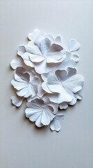 Close-up of a delicate arrangement of white paper flowers on a light gray background, showcasing intricate details and textures.