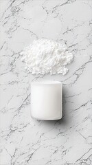 A minimalist composition featuring a pile of white powder and a white candle on a marble surface. The image is shot from above, creating a clean and modern aest