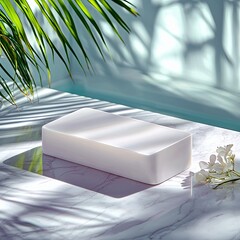 A white rectangular product display sits on a marble surface, with shadows of palm leaves and bright sunlight creating a serene atmosphere.