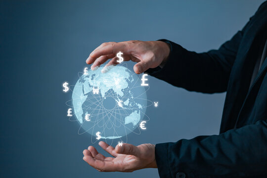 Businessman holding a glowing digital globe with currency symbols