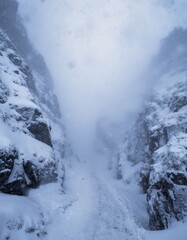 Snowy Pathway Through Rocky Landscape in Dense Winter Fog