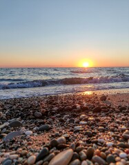 Serene Sunset Over Waves and Pebbles on Tranquil Beach Shoreline