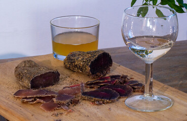 Glass of wine is on a table next to a piece of meat and a glass