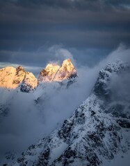 Majestic Snow-Capped Peaks Rising Above Clouds at Dusk