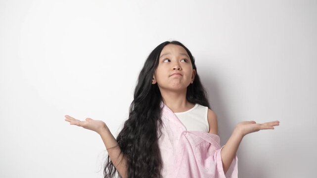 Confused young girl shrugs with hands raised, asking a question